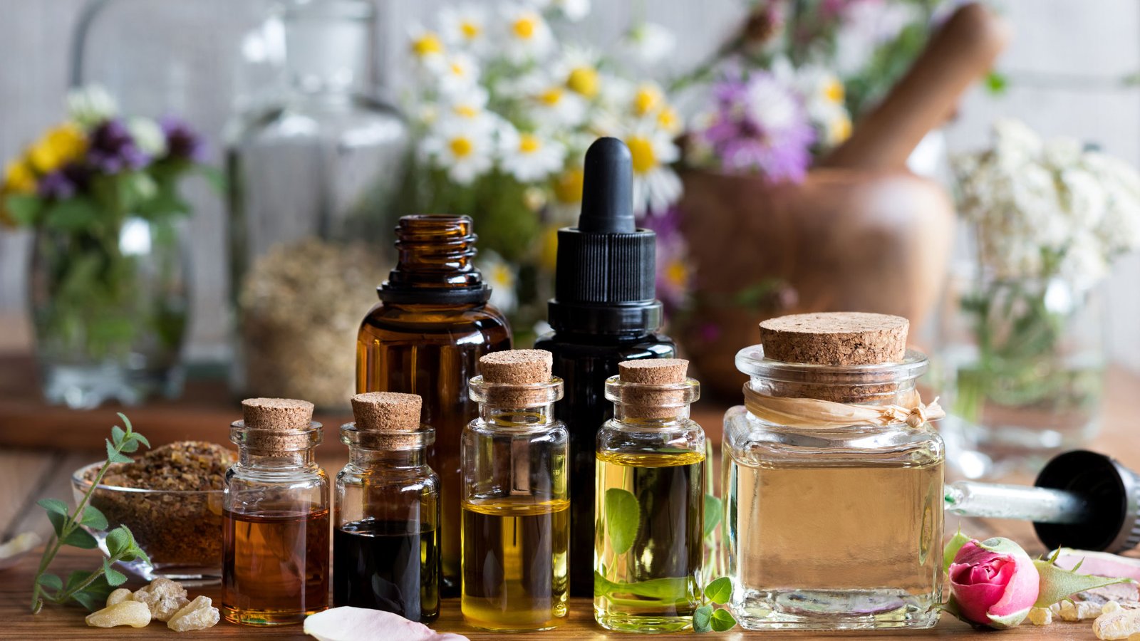 Different essential oils in a bottle, herbs and flowers